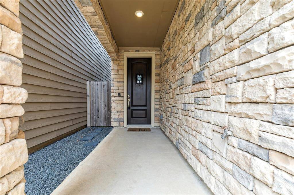 The front walkway is enhanced by the pretty stonework wall and the stained front door.  The gate on the left leads straight into the backyard.