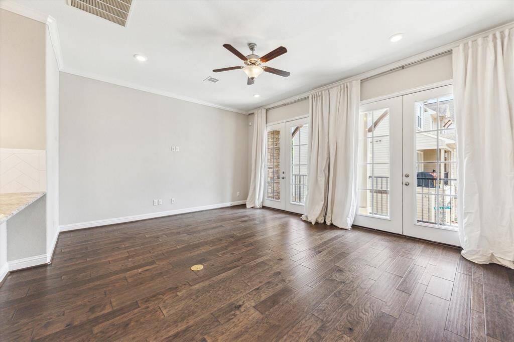 The living room with pretty French doors is well-sized and can accommodate large scale furnishings.    Floor to ceiling drapes add an additional touch of luxury to the space.