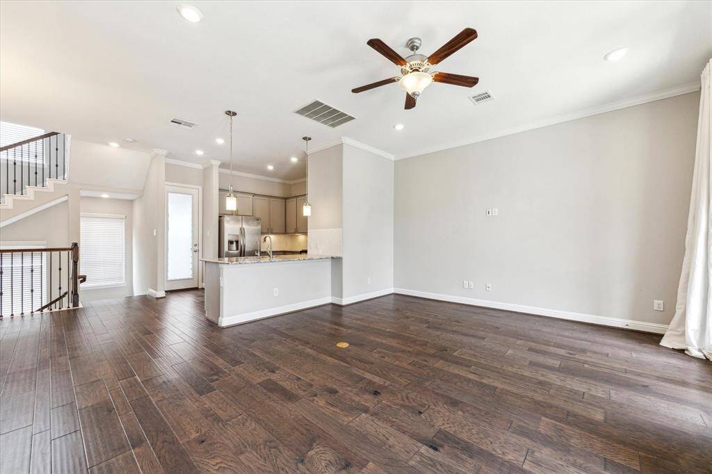 Family room looking back into kitchen.  You can see the thoughtful touches of recessed lighting, crown molding, pendant lights and ceiling fan.  The glass door in the kitchen leads out to a balcony space perfect for your grilling needs.