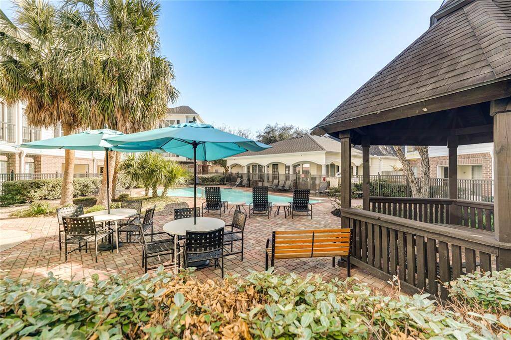 This photo features a charming outdoor space with a pool, shaded seating areas, and a wooden gazebo, surrounded by lush greenery and palm trees—ideal for relaxation and social gatherings.