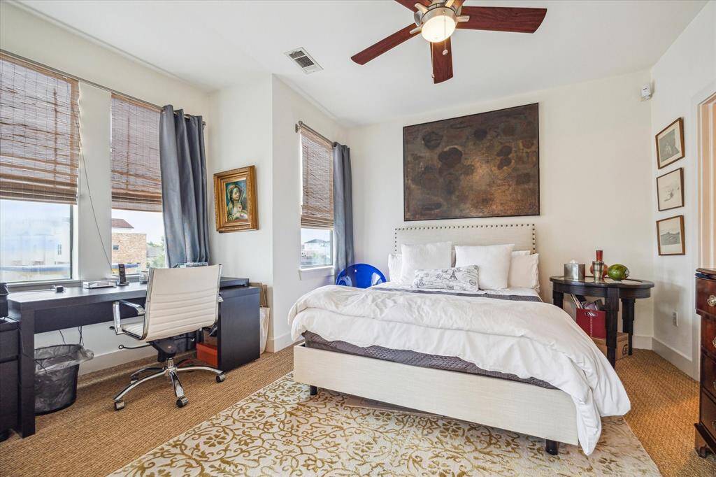 This bright second bedroom features a ceiling fan, and natural light from multiple windows.