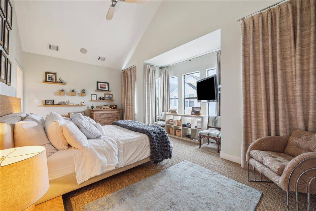 This spacious bedroom features high ceilings, plenty of natural light from large windows.