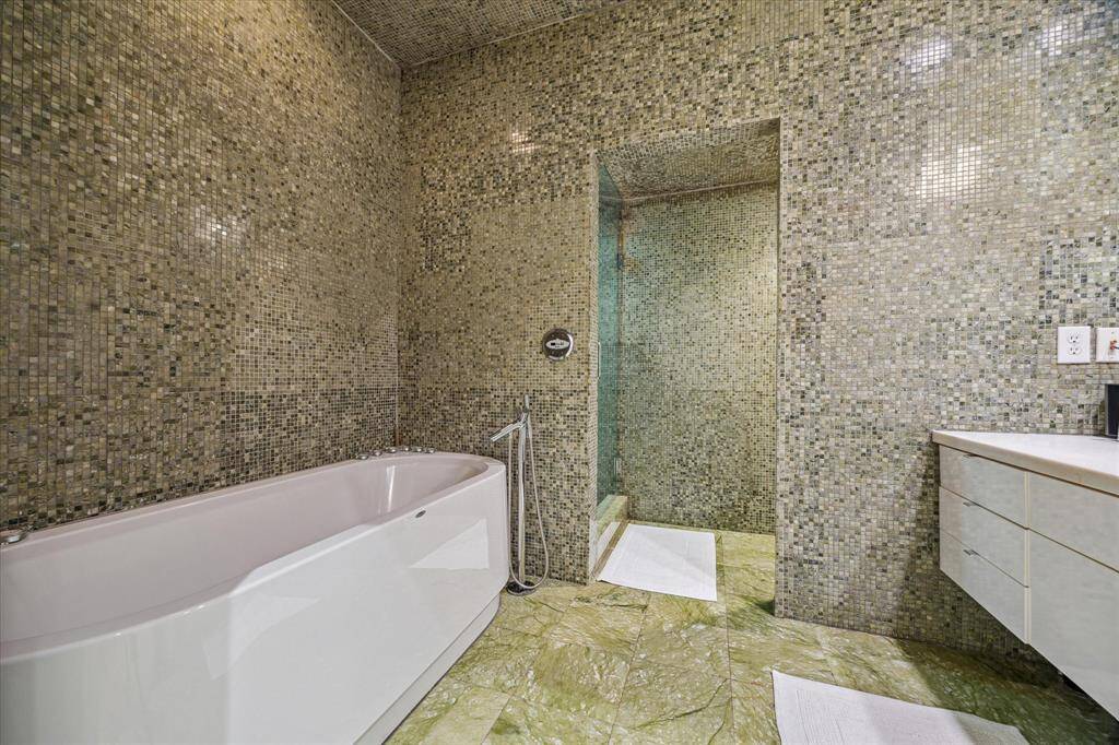 Luxurious bathroom featuring elegant mosaic tiles, a modern bathtub, and a spacious walk-in shower. The design is sleek and contemporary, offering a spa-like experience.