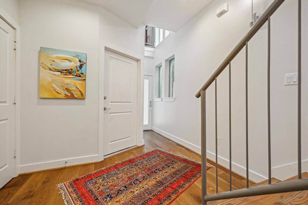 Bright entryway featuring hardwood floors, modern staircase. Natural light filters through upper windows, creating an inviting atmosphere.