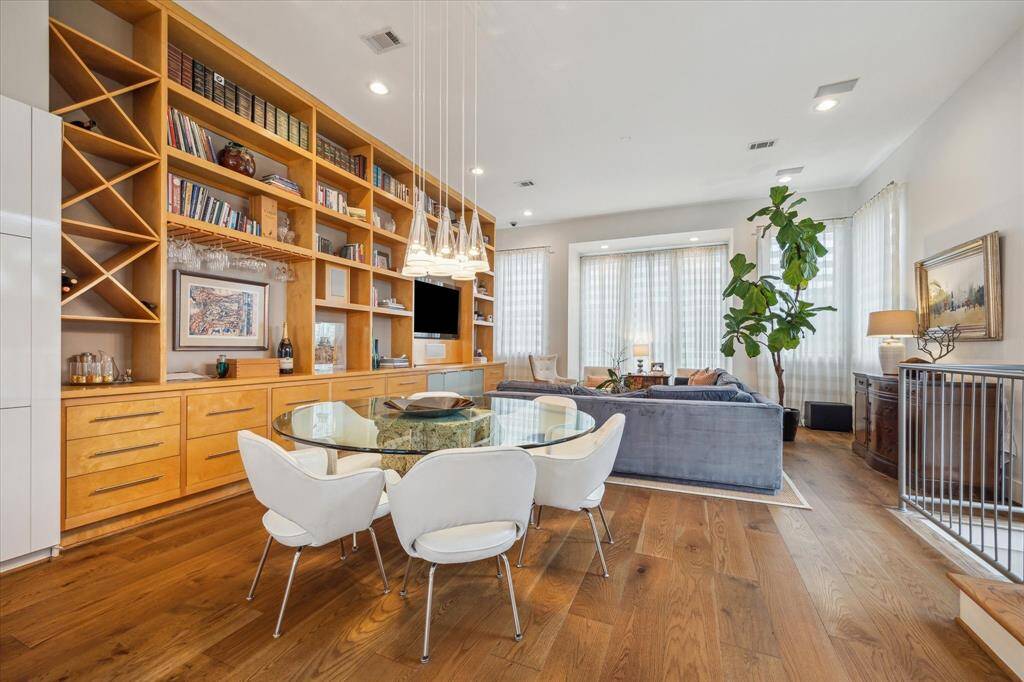 This inviting living space features a modern open layout with hardwood floors, a built-in wooden bookshelf, and ample natural light.