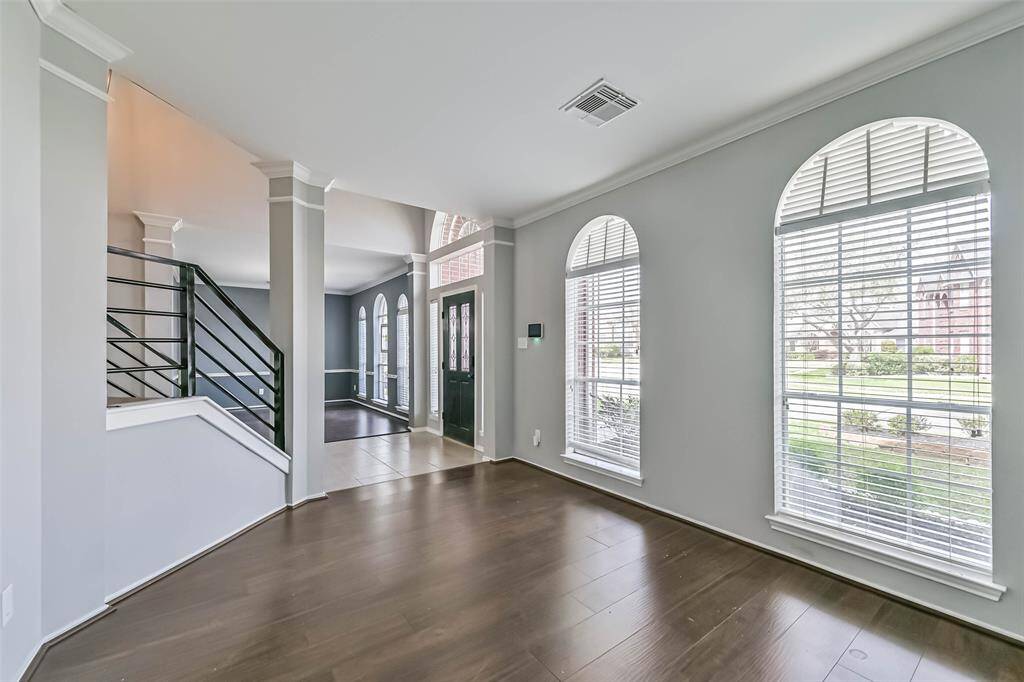 Bright, open entryway with large arched windows, hardwood floors, and a modern staircase. Perfect for welcoming guests.