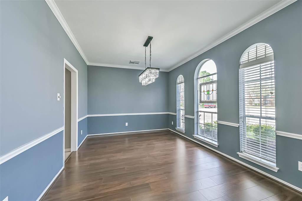Bright dining room with elegant arched windows, hardwood floors, and a contemporary chandelier. The blue-gray walls and white trim create a classic, sophisticated look.