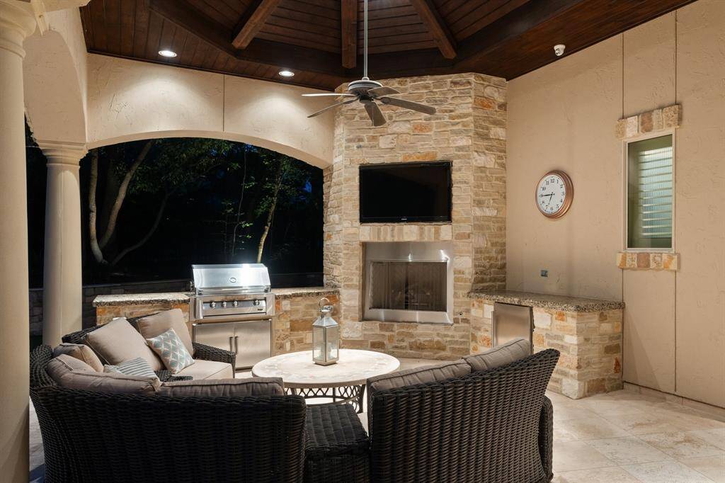 Beneath a wood finished ceiling, a gas fireplace; grill, mini fridge and abundant covered seating create an ideal space to relax.
