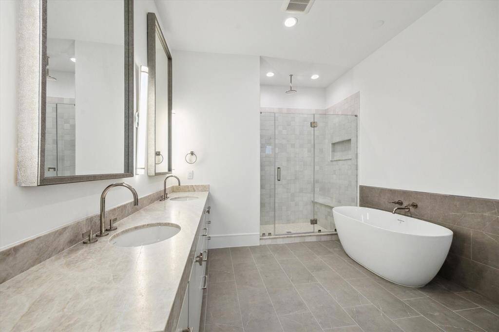 Primary bathroom features a Sterling Unwind freestanding oval soaking tub with Kallista One wall-mounted faucet, framed glass shower with Laticrete shower system.