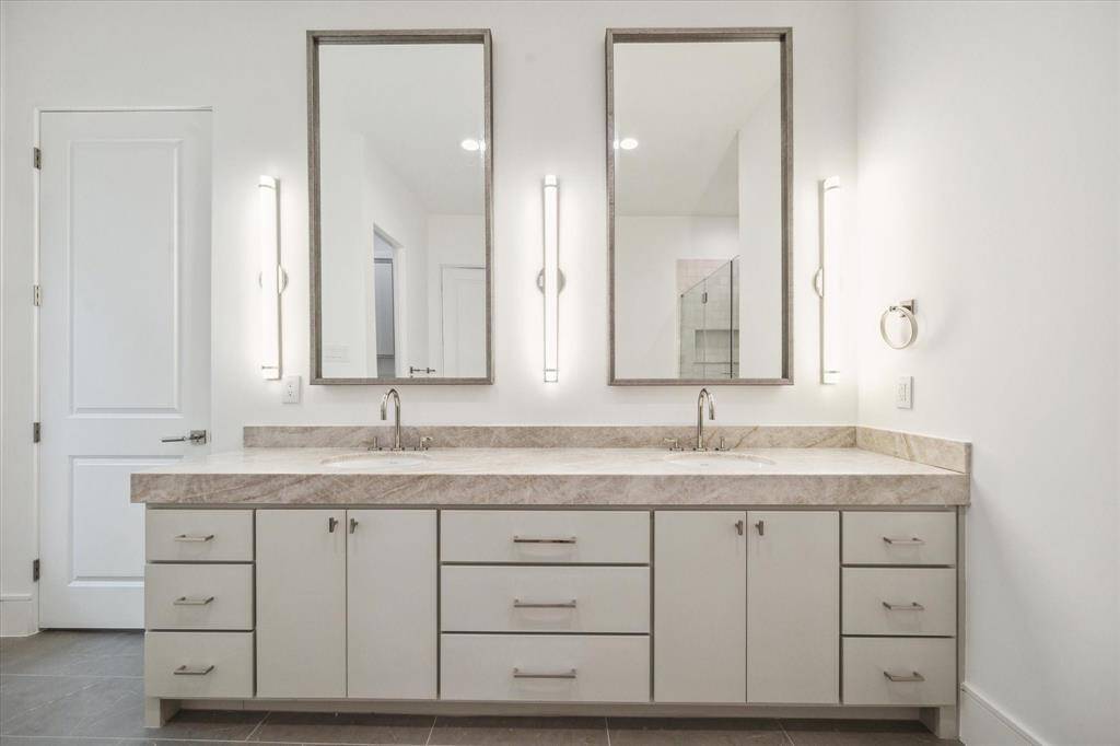 Custom Benedettini cabinetry, Leathered Taj Mahal Quartzite countertops, Kallista Perfect under-mount oval sinks with Kallista One fixtures, and sconces with polished nickel detail complete this luxurious bathroom.