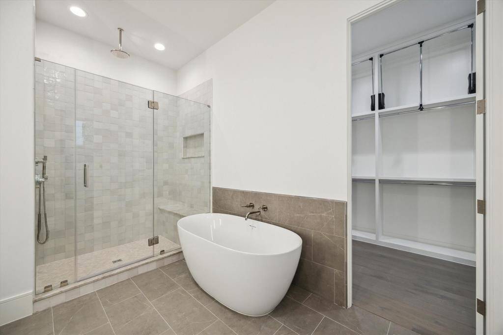 Shower features stacked square tile walls and niche with mosaic herribgone floor design and Laticrete rain shower head.