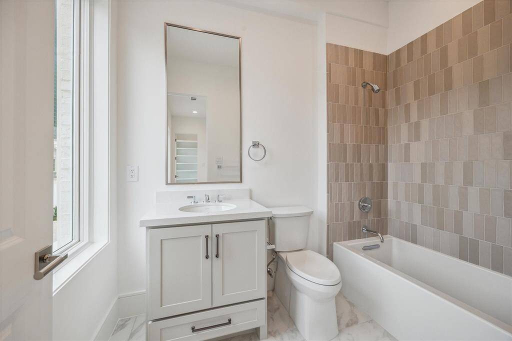 En-suite bath features Kohler Underscore alcove bath, Biancone Quartz countertops, and under-cabinet storage.