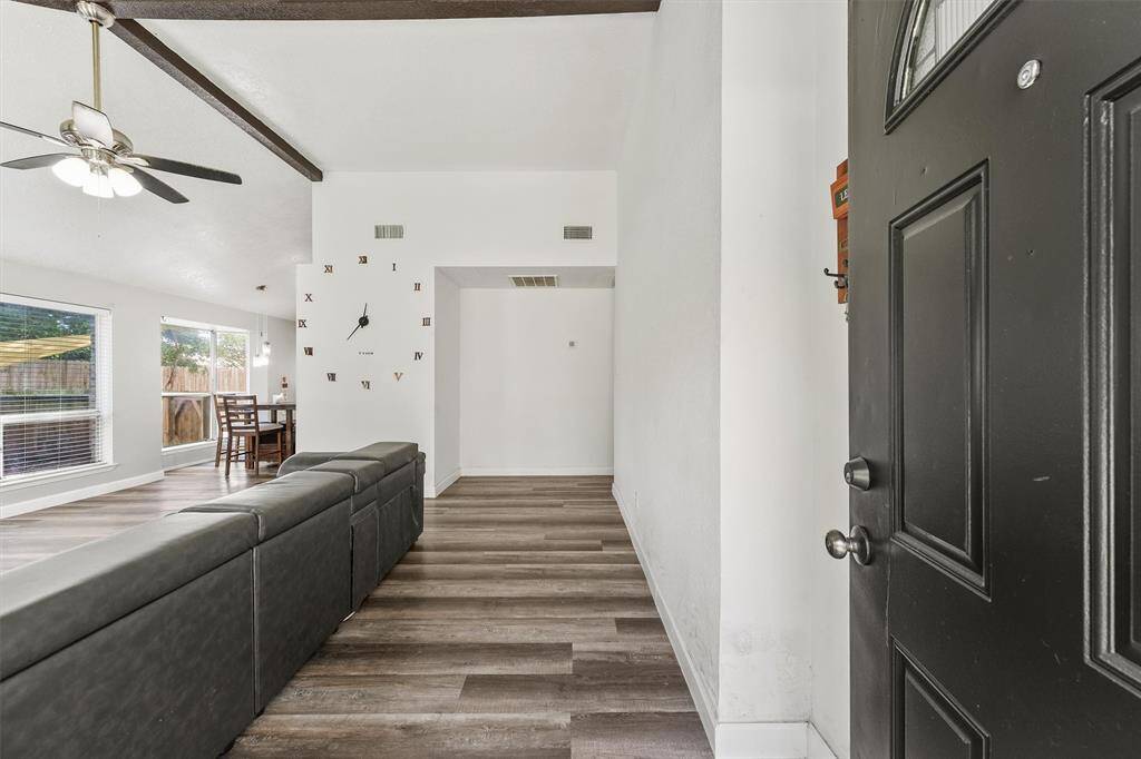 Step through the bold front door into a bright, open layout where natural light pours in and warm-toned floors guide you inside. With a clear line of sight to the heart of the home, this entry feels both spacious and inviting—ready to greet guests or offer a quiet return after a long day.