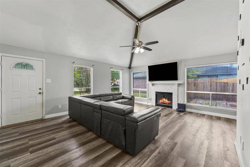 Soaked in natural light, this spacious living room features vaulted ceilings, a cozy fireplace, and wide-plank flooring that adds warmth and flow. It’s the perfect space to unwind, entertain, or simply feel at home.