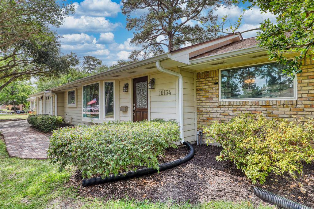 Charming single-story home with a mix of brick and siding exterior, lush landscaping, and a welcoming front entrance. The large windows provide ample natural light, and the pathway leads through a well-maintained garden. Ideal for those seeking a cozy and inviting residence.