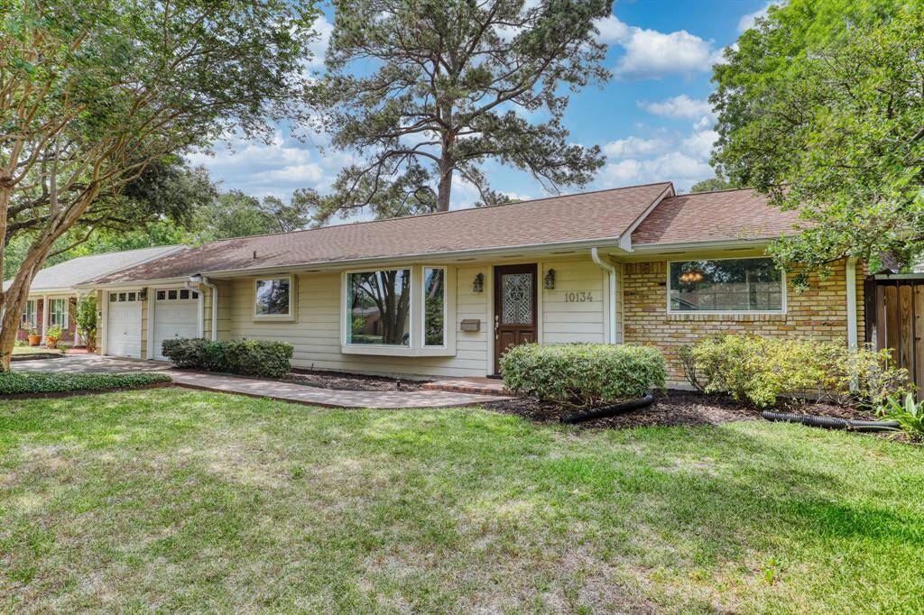 Charming single-story home with a brick and siding exterior, nestled in a lush, landscaped yard. Features large windows, a welcoming front entrance, and an attached garage. Ideal for comfortable family living in a serene neighborhood setting.
