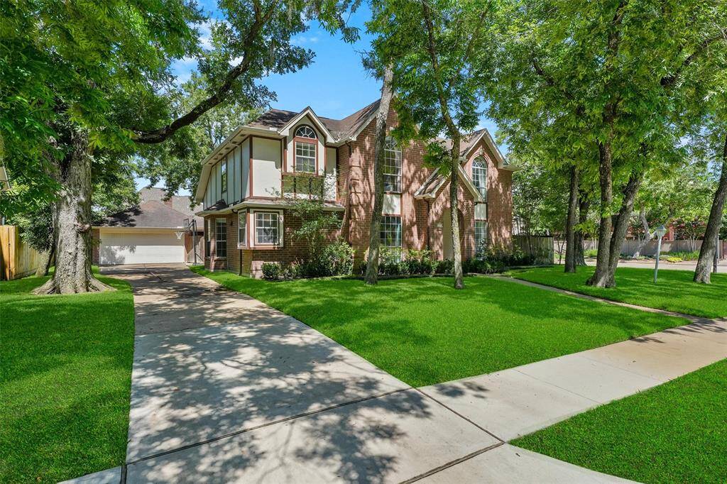 Welcome to 1017 Oak Knoll- Showcasing a charming two-story brick home with a beautifully manicured lawn and mature trees. A curved walkway leads to the entrance, and a quaint lamppost adds character to the front yard.