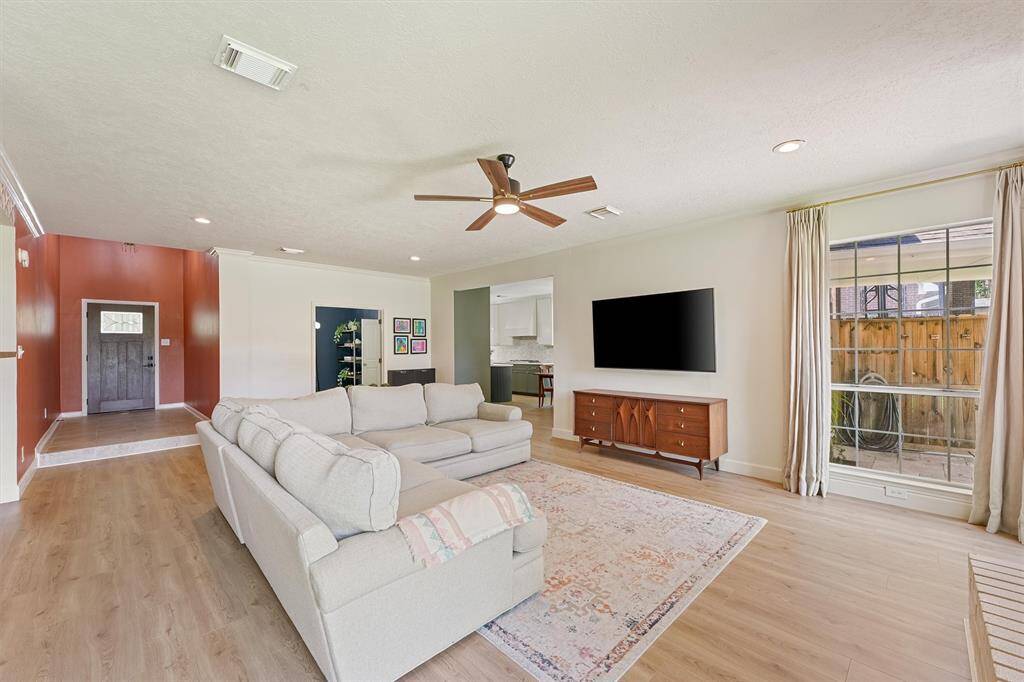 Relax in the family room with a cozy fireplace, large windows for natural light, and a patterned accent wall, creating a warm and modern atmosphere.
