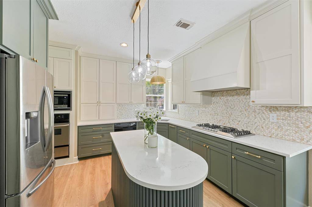 The secondary bathroom features a clean and bright design with a light-colored vanity, a sleek countertop, a large mirror, and a shower with a decorative curtain. A small plant adds a touch of greenery.