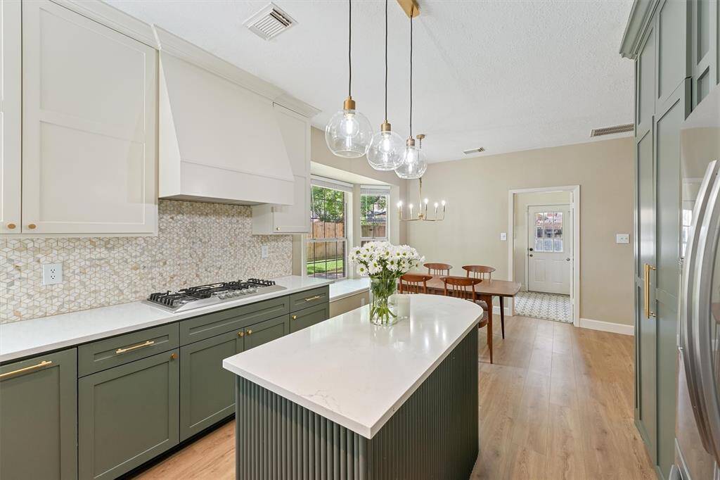 I'm sure you'll agree that this kitchen is beautiful! The space is bright with natural light from a large window and features two-tone cabinetry, a central island with pendant lighting, and a cozy dining area. Plus, I love the stylish wood flooring that ties the kitchen and dining area together. This modern kitchen with elegant design is truly a dream!