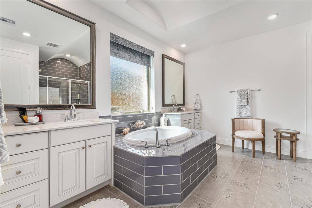 Luxurious primary bathroom featuring elegant finishes, a soaking tub, and ample natural light.