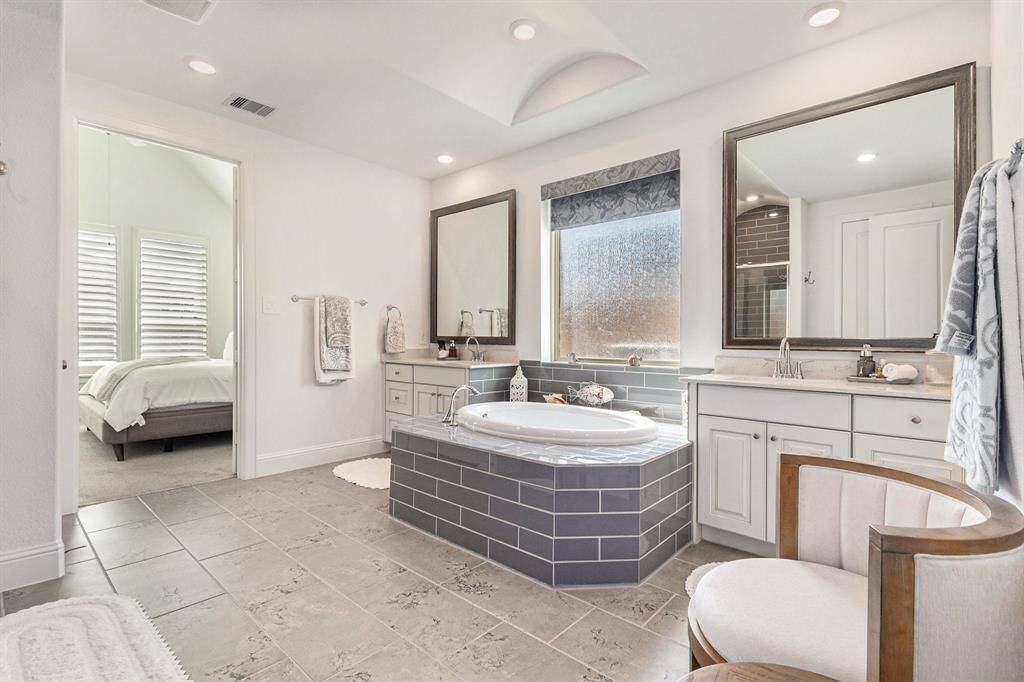 Luxurious primary bathroom featuring a spa-like tub, dual vanities, and elegant finishes.