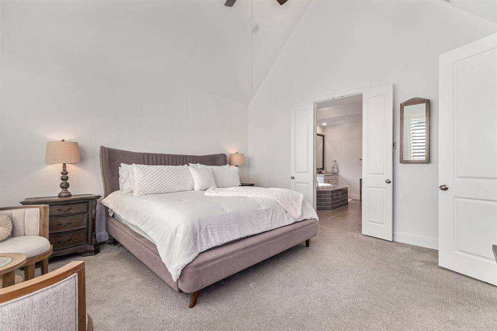 Primary bedroom featuring vaulted ceilings, abundant natural light, and an elegant ensuite bathroom. Perfect for relaxation and comfort.
