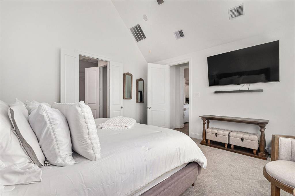 Primary bedroom featuring vaulted ceilings and a seamless flow into the elegant en-suite bathroom.
