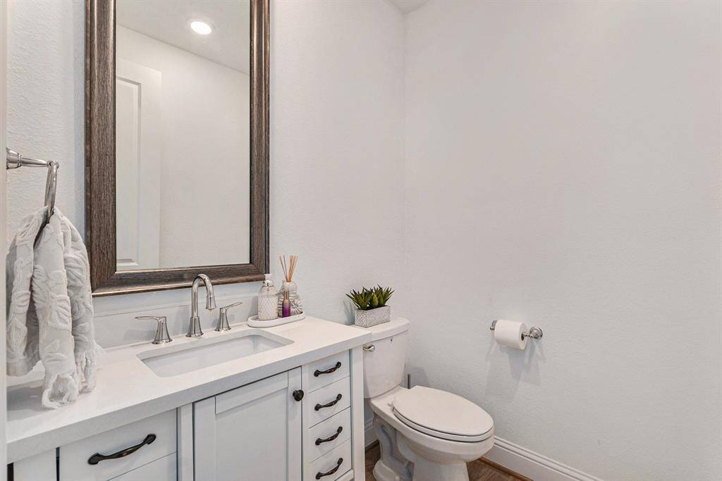 Sleek and modern half bathroom featuring a stylish vanity, large framed mirror, and elegant fixtures.