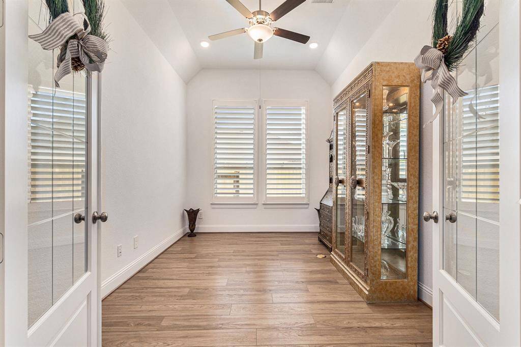 This inviting home office features elegant double doors, ample natural light, and a stylish wood floor, creating the perfect environment for productivity and focus.