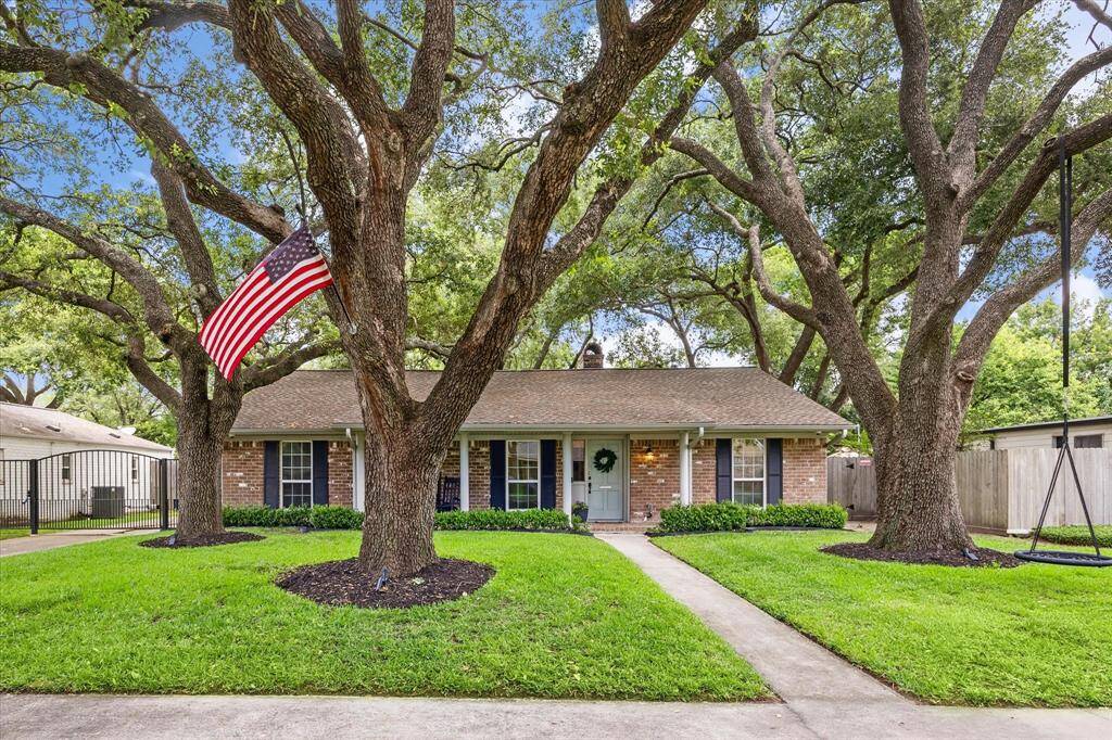 Charming brick home with a cozy front porch, nestled among mature trees. Features a well-maintained lawn, ideal for a welcoming, tranquil setting.