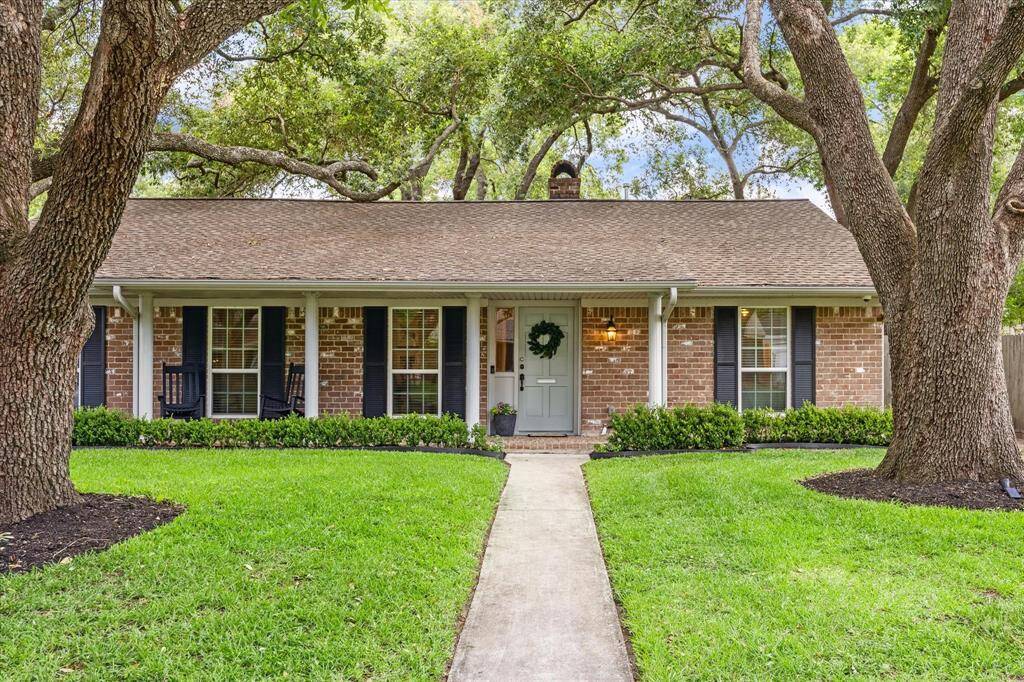 Charming brick home with a welcoming front porch and well-maintained landscaping. Features a lush green lawn, mature trees, and a pathway leading to the entrance. Ideal for comfortable family living.