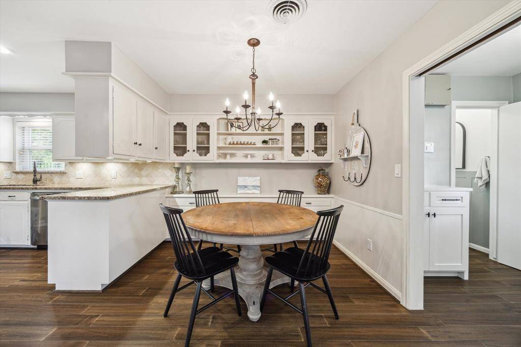 This charming dining nook features built-in white cabinetry with decorative glass doors. A stylish chandelier adds elegance, while open shelving and tasteful decor create a cozy, inviting atmosphere.