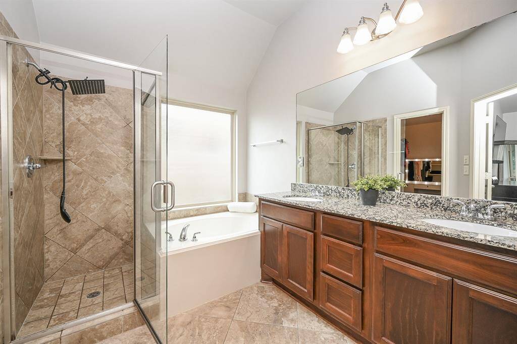 Beautiful bathroom featuring a walk-in shower with a luxurious rain head. Next to it, a  soaking tub invites relaxation, set against a large privacy window bringing in natural light. The space combines style and comfort, creating a serene, spa-like retreat