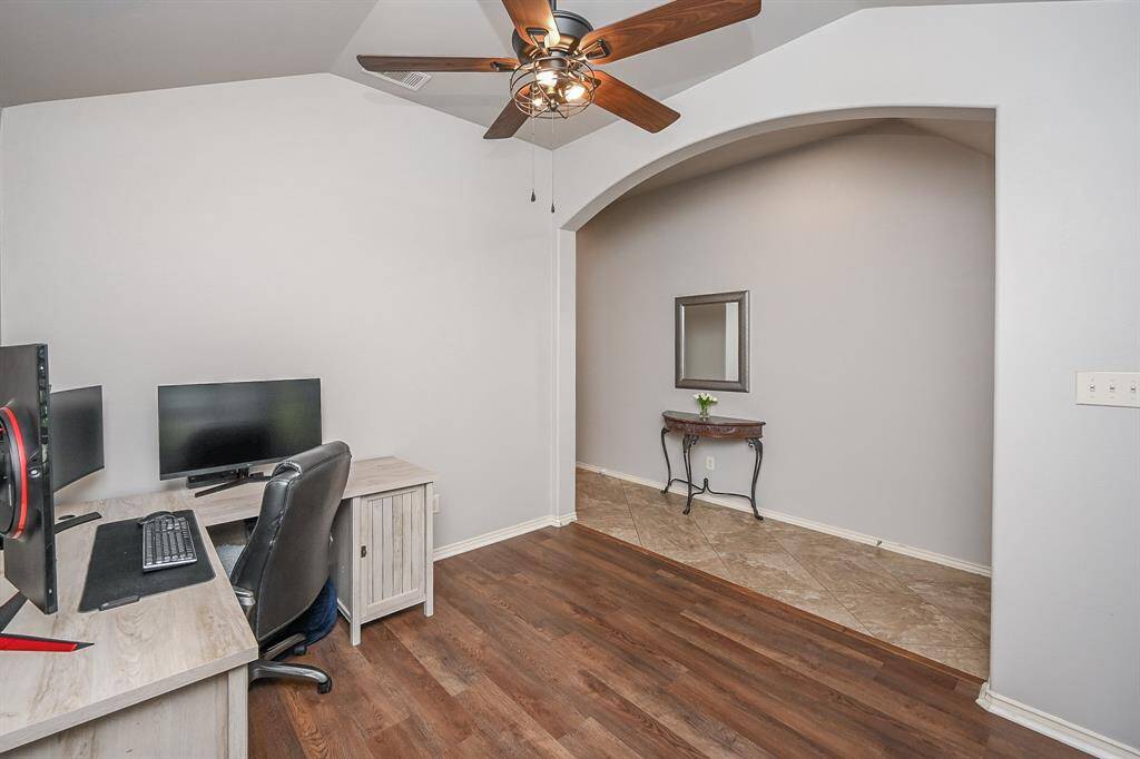 This room features a large wall to wall window with elegant  plantation shutters and wood floors. Impressive tall coffered ceilings and a ceiling fan.
