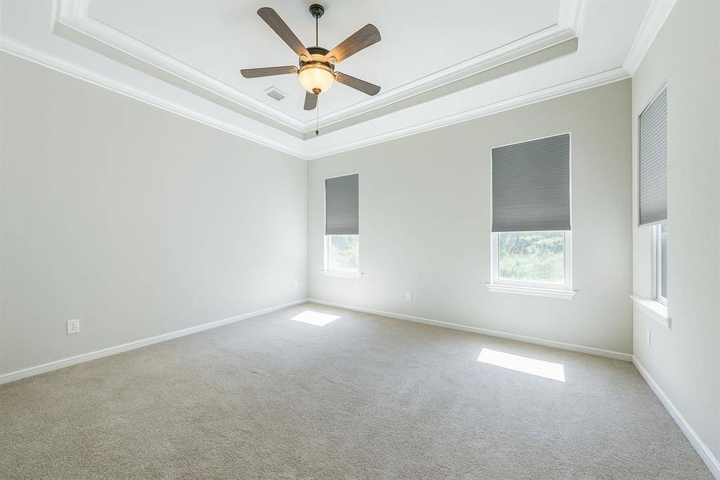 Come home and unwind in this lovely primary suite! Enjoy the warm and relaxing environment with plenty of space for your king size bed, dresser and a chair and table by the windows. Featuring a tray ceiling with crown molding, plush carpet for comfort and custom built-ins in closet.