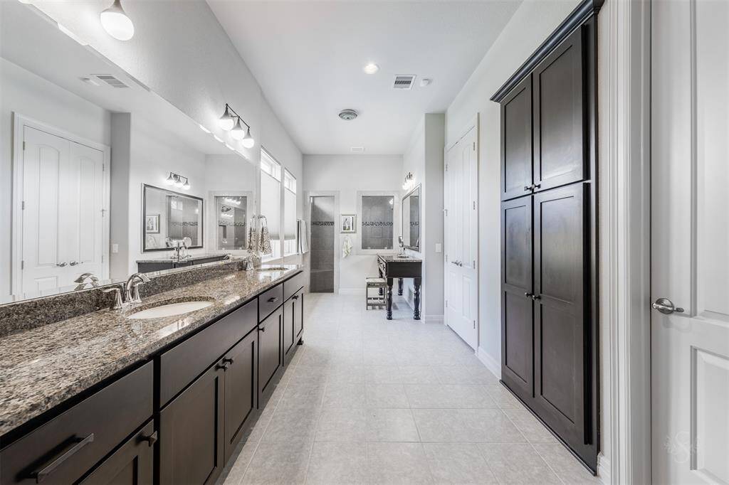 Step into the lovely upgraded primary bath featuring an extended vanity counter with double sinks, enclosed shower with tile surround, built-in makeup desk & mirror and huge custom built-in closet.
