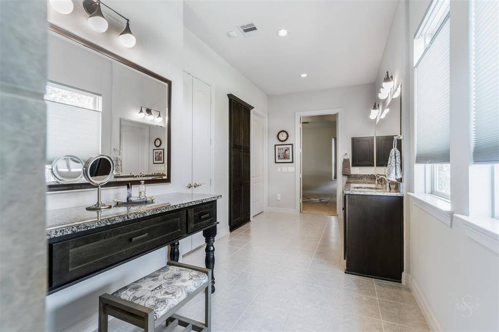 Step into the lovely upgraded primary bath featuring an extended vanity counter with double sinks, enclosed shower with tile surround, built-in makeup desk & framed mirror and huge custom built-in closet.