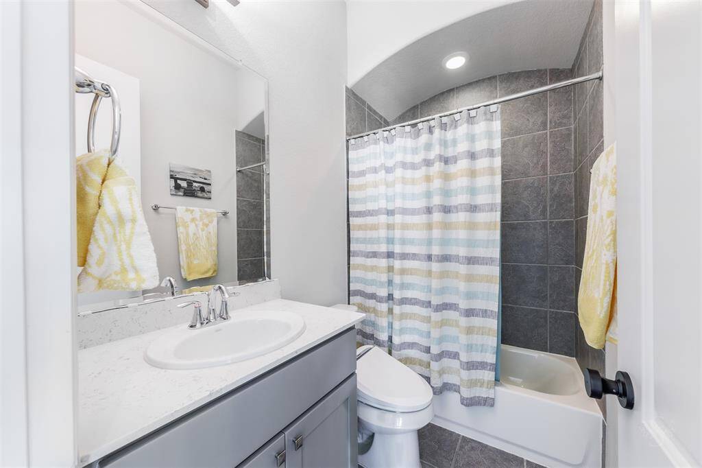 This secondary full bath provides a Quartz vanity and bath/shower combination with tile surround.