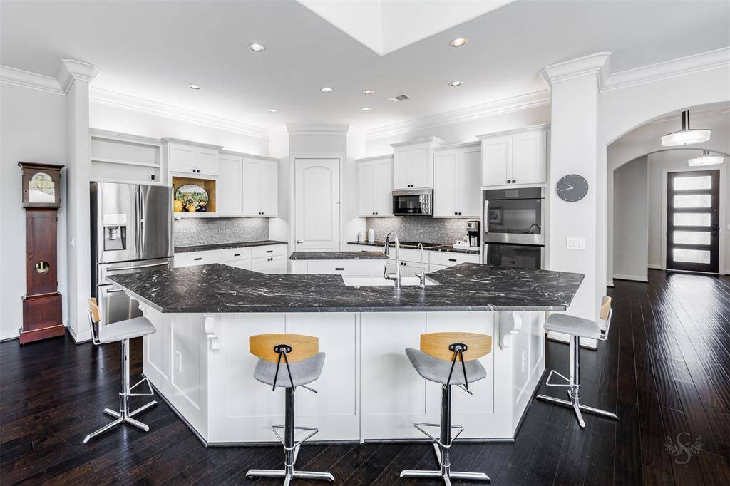 A kitchen fit for a Chef! This sensational designer kitchen showcases exquisite upgraded granite countertops including a huge island with breakfast bar and also a center island, stainless steel appliances including GE double ovens, Whirlpool microwave, gas cooktop, crisp white cabinetry and custom backsplash highlighted by recessed and cabinet lighting.