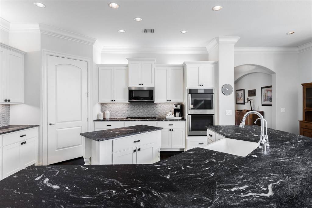 A kitchen fit for a Chef! This sensational designer kitchen showcases exquisite upgraded granite countertops including a huge island with breakfast bar and also a center island, stainless steel appliances including GE double ovens, Whirlpool microwave, gas cooktop, crisp white cabinetry and custom backsplash highlighted by recessed and cabinet lighting.