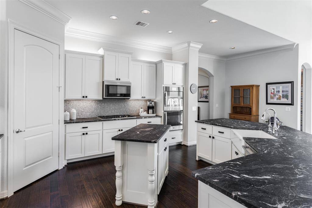Kitchen boasts upgraded granite ($6700), above and below, cabinet lighting, Kohler farm sink, GE double ovens and a Whirlpool microwave.
