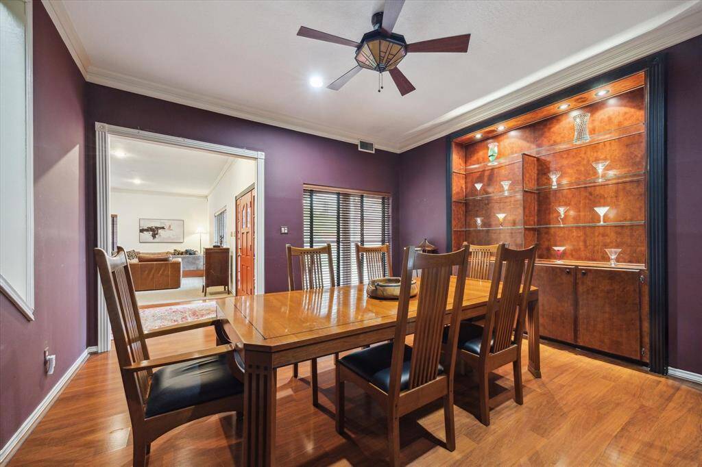 Rear House: Dining room features rich purple walls and wooden flooring. A display cabinet with accent lighting adds elegance, and a ceiling fan completes the cozy ambiance. The room opens into a spacious living area, enhancing the open-concept feel.