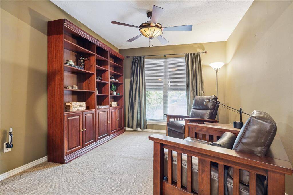 Rear House: Cozy reading den inside the primary bedroom with built-in wooden bookshelves and large window offering natural light. Ideal for relaxation and study.
