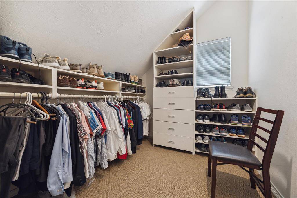 Rear House: Spacious primary walk-in closet with ample shelving and hanging space, neatly organizing clothing and shoes. It features a window for natural light.