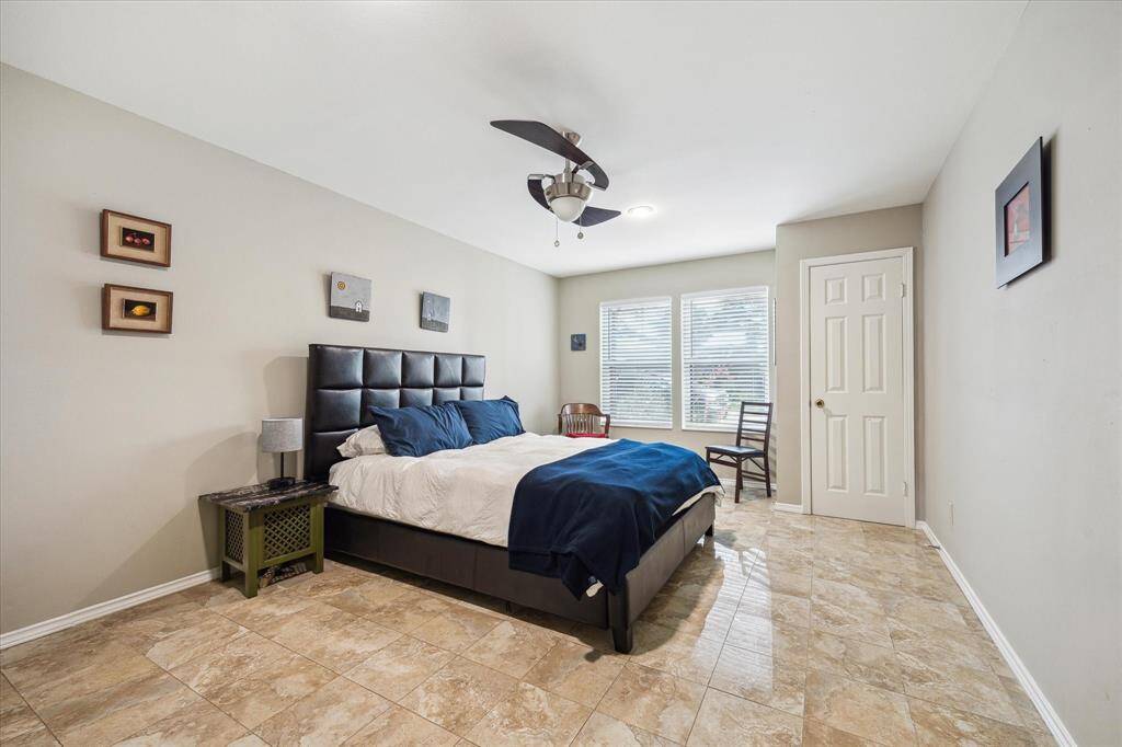 Front House: Another view of this spacious bedroom with tiled flooring. Natural light streams through dual windows.
