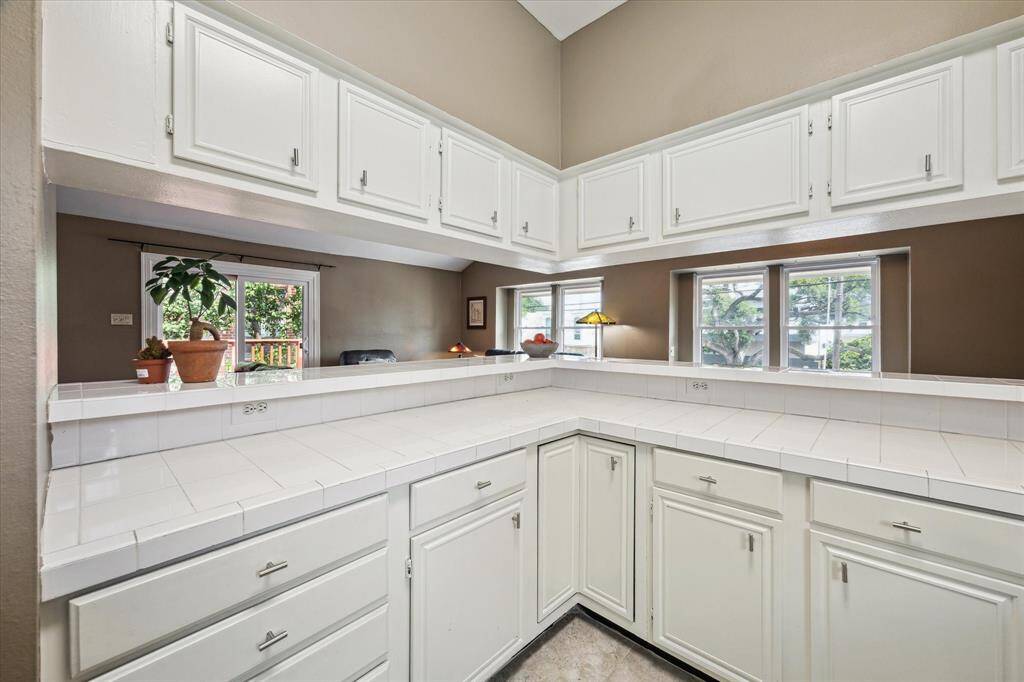 Front House: Another view of the kitchen features ample natural light from windows offering a view of the greenery outside. Open layout enhances the space, perfect for cooking and socializing.
