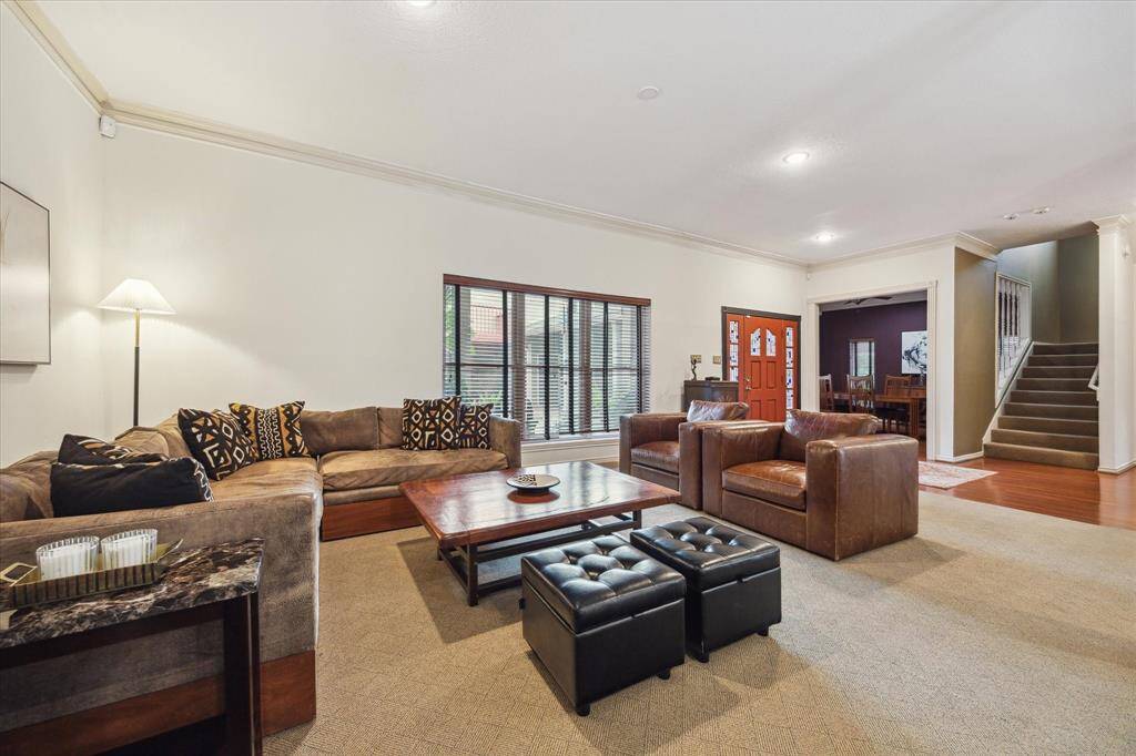Rear House: View of  living room features a warm, neutral color palette with carpeted flooring, modern lighting, and a window allowing natural light.