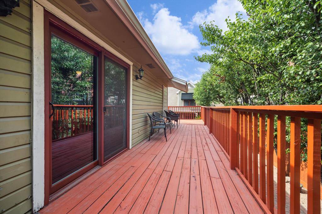 Rear House: Wooden wraparound deck featuring seating and surrounded by greenery. It has sliding glass doors leading into the home and offers a peaceful outdoor space perfect for relaxation or entertaining.