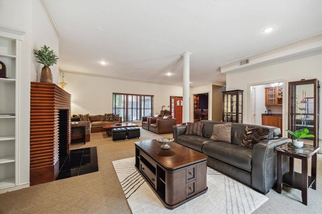 Rear House: Another view of the living room with a cozy, open layout features a mix of contemporary and classic decor. It includes a fireplace, built-in shelves, and ample seating. Large windows offer plenty of natural light, and the space leads into a visible dining area and kitchen.